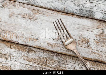 Comprimés avec fourche argent sur une vieille table en bois avec peinture blanche Banque D'Images