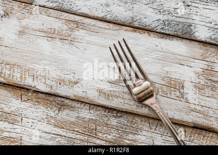 Comprimés avec fourche argent sur une vieille table en bois avec peinture blanche Banque D'Images