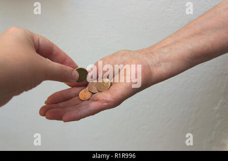 Un jeune caucasien donne la main d'une personne âgée l'aumône pour qu'il puisse avoir le minimum nécessaire pour vivre. Banque D'Images