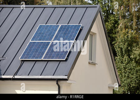 Panneaux solaires installés et utilisés pour l'énergie verte renouvelable propre écologique sur dark metal toit du foyer rural. Banque D'Images