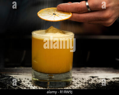 Barman saupoudre les puces orange et cocktail avec du sucre en poudre Banque D'Images