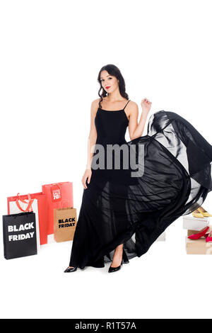 Jolie femme en robe noire qui posent avec les chaussures et sacs shopping autour de isolated on white Banque D'Images