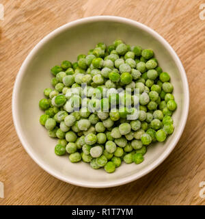 Pois verts congelés dans un bol sur fond de table en bois Banque D'Images