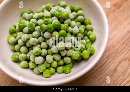 Pois verts congelés dans un bol sur fond de table en bois Banque D'Images