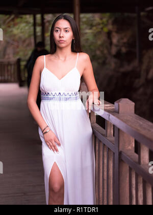 Belle fille brune en robe blanche à l'écart dans le parc Banque D'Images