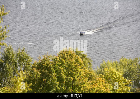 Petit bateau naviguant sur la rivière sur un fond d'arbres. Banque D'Images