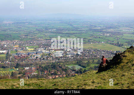 Malvern, Royaume-Uni - 29 mars 2012 : une femme d'âge moyen et son chien labrador noir s'asseoir et se reposer en face de la vue sur la campagne du Worcestershire Malvern et pendant la marche de la Worcestershire Beacon en haut de la promenade Malvern Hills, Worcestershire, Royaume-Uni Banque D'Images