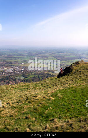 Malvern, Royaume-Uni - 29 mars 2012 : une femme d'âge moyen et son chien labrador noir s'asseoir et se reposer en face de la vue sur la campagne du Worcestershire Malvern et pendant la marche de la Worcestershire Beacon en haut de la promenade Malvern Hills, Worcestershire, Royaume-Uni Banque D'Images