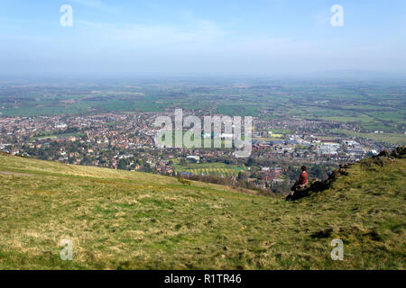 Malvern, Royaume-Uni - 29 mars 2012 : une femme d'âge moyen et son chien labrador noir s'asseoir et se reposer en face de la vue sur la campagne du Worcestershire Malvern et pendant la marche de la Worcestershire Beacon en haut de la promenade Malvern Hills, Worcestershire, Royaume-Uni Banque D'Images