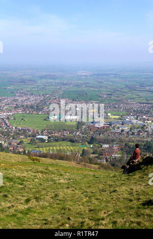 Malvern, Royaume-Uni - 29 mars 2012 : une femme d'âge moyen et son chien labrador noir s'asseoir et se reposer en face de la vue sur la campagne du Worcestershire Malvern et pendant la marche de la Worcestershire Beacon en haut de la promenade Malvern Hills, Worcestershire, Royaume-Uni Banque D'Images