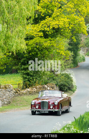 La conduite de l'automobiliste 1961 Alvis TD21 britannique fait DHC Series 1 drophead coupe ooupe voiture de collection sur chemin de campagne dans les Cotswolds, en Angleterre Banque D'Images