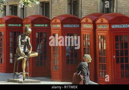 Téléphone rouge les cases à côté des jeunes danseurs statue en bronze, Covent Garden, Londres, Angleterre, Royaume-Uni. Banque D'Images