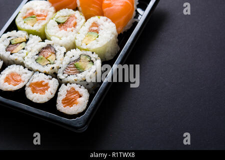 La nourriture japonaise : maki et nigiri sushi situé sur fond noir. Copyspace Banque D'Images