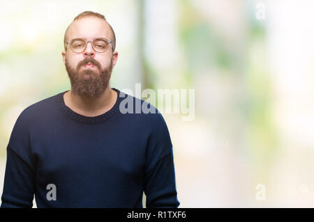 Hipster Young caucasian man wearing sunglasses sur fond isolé que quelques bouffées joues avec drôle de visage. Bouche gonflé à l'air, l'expression fou. Banque D'Images