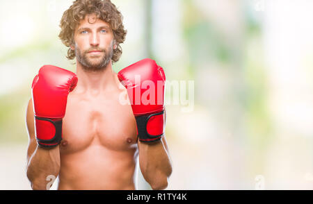 Handsome young man wearing boxing gloves boxer sur fond isolé avec expression grave sur le visage. Simple et naturelle à la recherche de l'appareil photo. Banque D'Images
