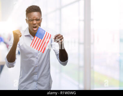 Young african american man holding USA flag contrarié et frustré de crier avec colère, fou et hurlant de main levée, la colère concept Banque D'Images