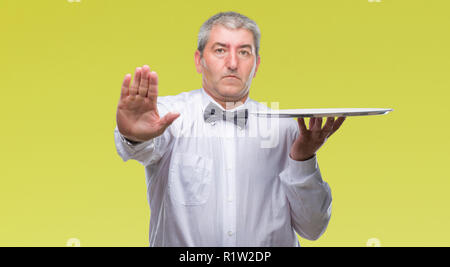 Beau garçon senior man holding silver tray sur fond isolé avec main ouverte faisant stop avec de sérieux et de confiance, la défense de l'expression Banque D'Images