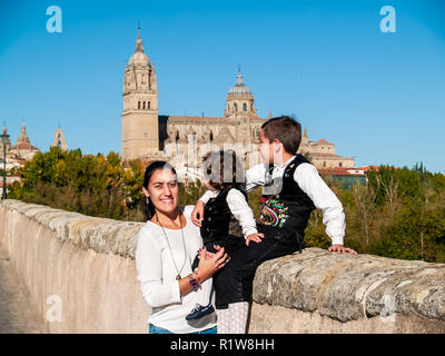 Une femme et deux enfants sur l'embrassé frères pont romain de Salamanque, vêtu de vêtements traditionnels et de la cathédrale de Salamanque Banque D'Images