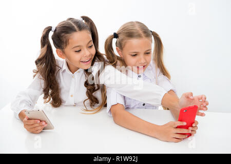 La relâche scolaire pour professionnels de petites filles à l'aide de smartphones. Les petites filles à l'aide de smartphones sur les congés scolaires s'amusant Banque D'Images