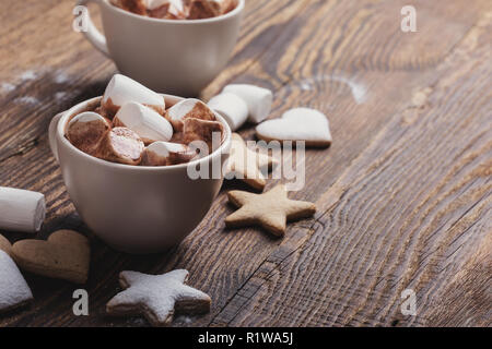 Biscuits de Noël plaque saupoudrée de sucre en poudre et de tasses de chocolat chaud avec des guimauves sur table en bois Banque D'Images