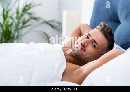 Portrait of happy hot man laying in bed at home Banque D'Images