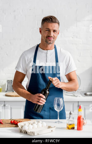 Homme adulte ouverture d'une bouteille de vin à cuisine Banque D'Images