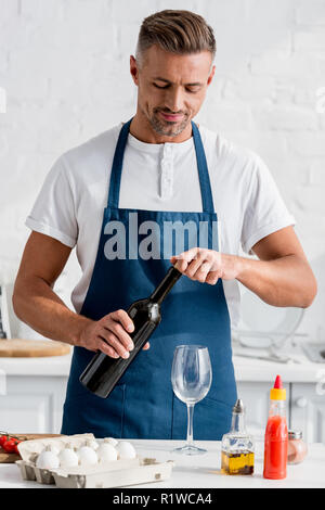 Homme adulte ouverture d'une bouteille de vin à cuisine Banque D'Images