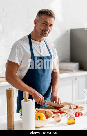 Hot man cutting chili pepper on cutting board sur la cuisine Banque D'Images