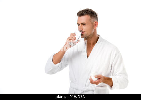 Homme adulte en peignoir prendre des pilules avec un verre d'eau isolé sur blanc Banque D'Images