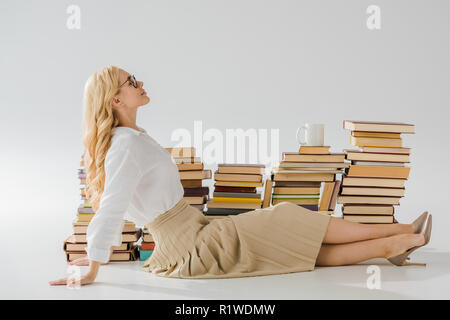 Belle femme assise sur le plancher près de pile de livres Banque D'Images