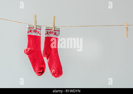 Close up of red Winter socks fête pendaison sur corde à linge avec isolé sur gray Banque D'Images
