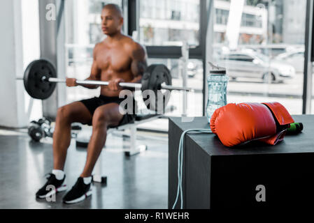 Vue rapprochée de gant de boxe, la corde à sauter et bouteille d'eau et de levage de sportif derrière barbell in gym Banque D'Images