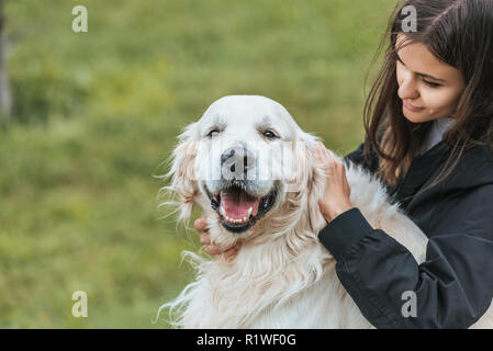 Belle jeune femme caressant adorable retriever dog in park
