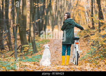 Jeune femme en location et son golden retriever assis près de sur les forêts en chemin jaune Banque D'Images