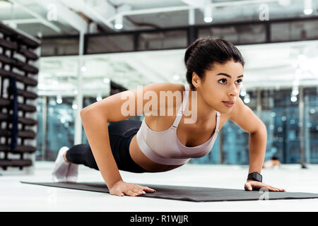 Belle jeune fille faire poussez se lève sur le tapis de fitness gym Banque D'Images