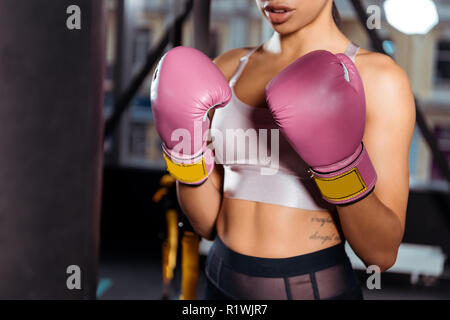 Vue partielle de strong girl à des gants de boxe boxe pratiquer dans une salle de sport Banque D'Images