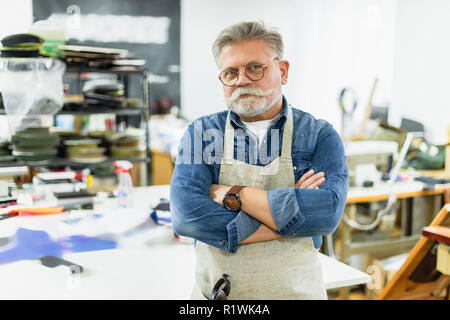 Mâle mature craftsman in apron posant avec bras croisés en atelier Banque D'Images