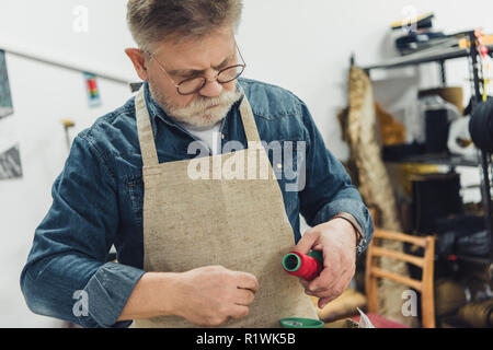 Mâle mature craftsman in apron travailler avec des chaînes au studio Banque D'Images