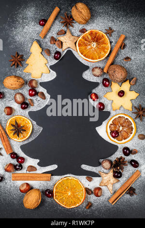 Forme d'arbre de Noël de sucre glace sur fond sombre avec les noix, les canneberges, l'anis étoilé, les noix de pin, les cookies et les tranches d'orange Banque D'Images