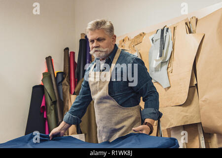 Sac à main homme confiant mettre artisan tissu sur la table de travail au studio Banque D'Images