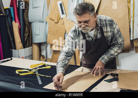 Sac à main en cuir hommes mûrs sérieux artisan en tablier et au studio de travail lunettes Banque D'Images