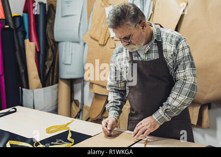 Sac à main en cuir hommes mûrs artisan en tablier et au studio de travail lunettes Banque D'Images