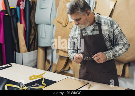 Sac à main en cuir homme artisan en travaillant au studio tablier Banque D'Images