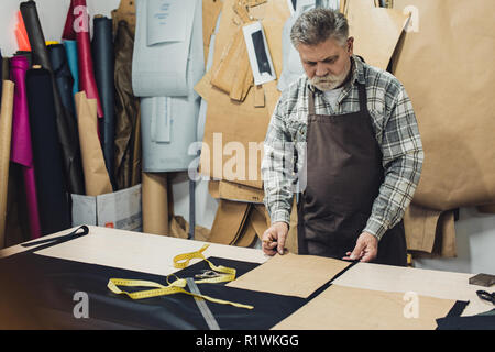 Sac à main en cuir mature artisan en travaillant au studio tablier Banque D'Images