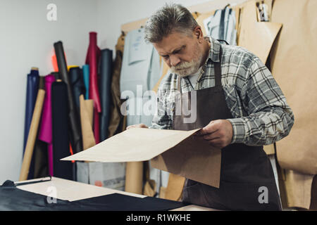 Sac à main mature artisan en regardant l'aire à l'atelier en carton Banque D'Images