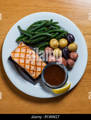 Délicieux saumon grillé servi sur une planche de cèdre avec bébé pommes de terre et haricots verts Banque D'Images