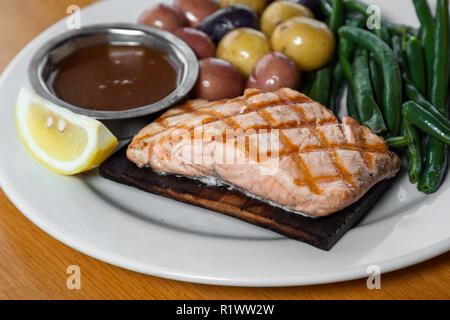 Délicieux saumon grillé servi sur une planche de cèdre avec bébé pommes de terre et haricots verts Banque D'Images