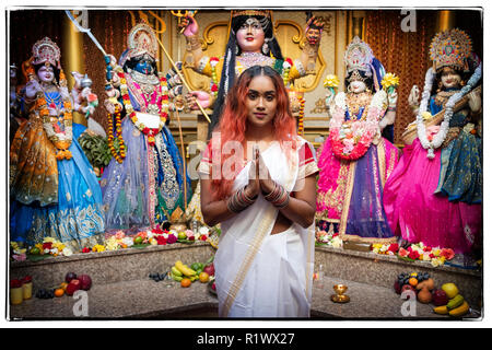 Portrait d'une belle jeune femme hindoue en face des statues de divinités dans un temple dans le Queens, New York. Banque D'Images