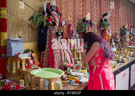 Un jeune dévot hindou fait une offrande de fleurs à la déesse Kali dans un temple hindou de Shakti dans le Queens, New York. Banque D'Images