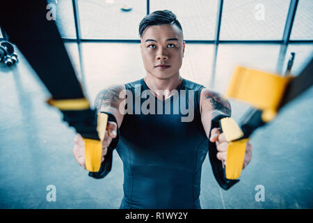 Jeune sportif musculaire ciblée formation avec bandes de résistance in gym Banque D'Images